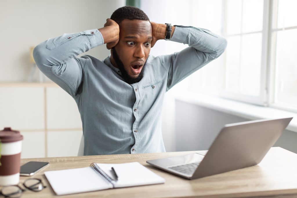 Shocked African Businessman Having Issue Working On Laptop In Office